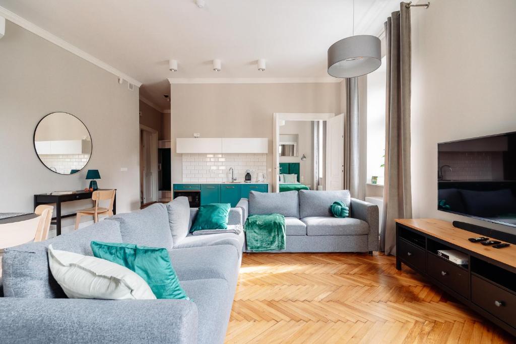 Kochanowskiego Family Apartments في كراكوف: غرفة معيشة مع أريكة وتلفزيون