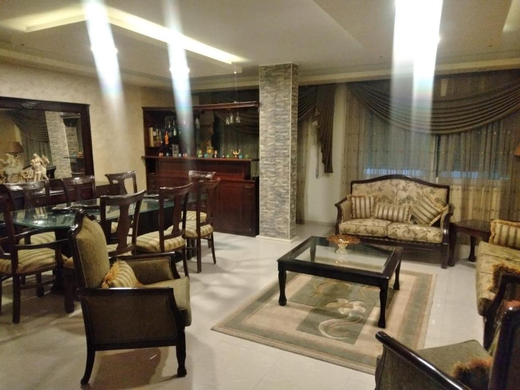 ein Wohnzimmer mit einem Sofa, Tischen und Stühlen in der Unterkunft City Center Furnished Apartment in Madaba