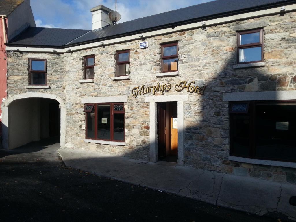 un bâtiment en briques avec un panneau indiquant l'heure des sandwichs dans l'établissement Murphys Hotel, à Tinahely