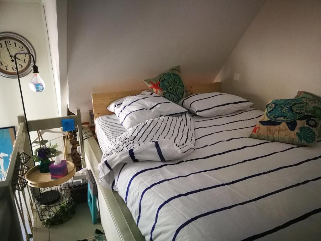 a bedroom with a bed with striped sheets and a clock at Study du pêcheur in Trouville-sur-Mer