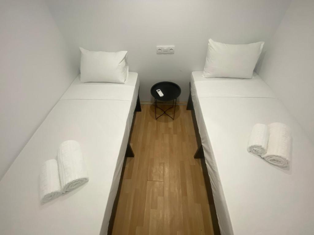 Le.Chris Central Dorms في مدينة ريثيمنو: سريرين في غرفة مع ملاءات بيضاء ومناشف