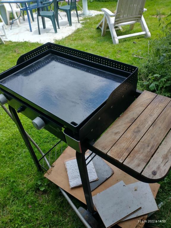a barbecue grill with a wooden table and a bench at Une pause... Quelque part in Le Torp-Mesnil