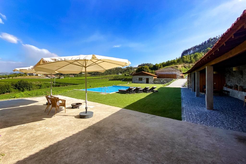 une terrasse avec un parasol et une piscine dans l'établissement The FarmHouse II - Uma quinta deslumbrante, à Felgueiras