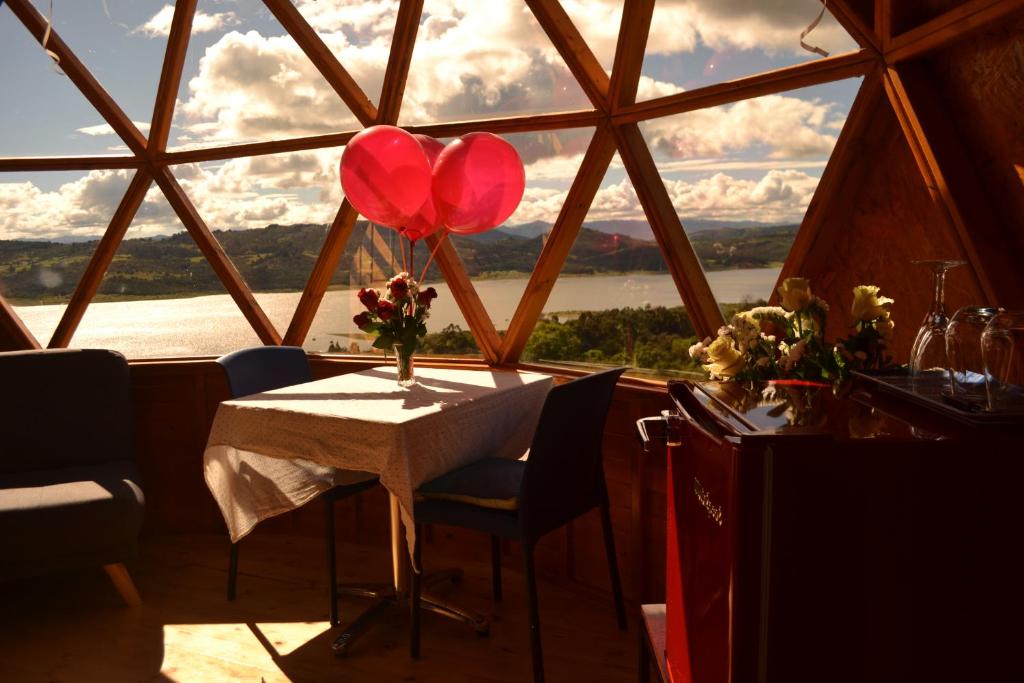 una mesa con dos globos rojos delante de una ventana en Arrecife Glamping, en Guatavita