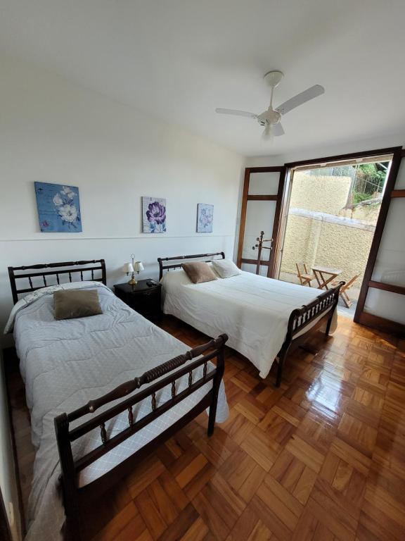 a bedroom with two beds and a large window at Pousada Valparaiso in Petrópolis