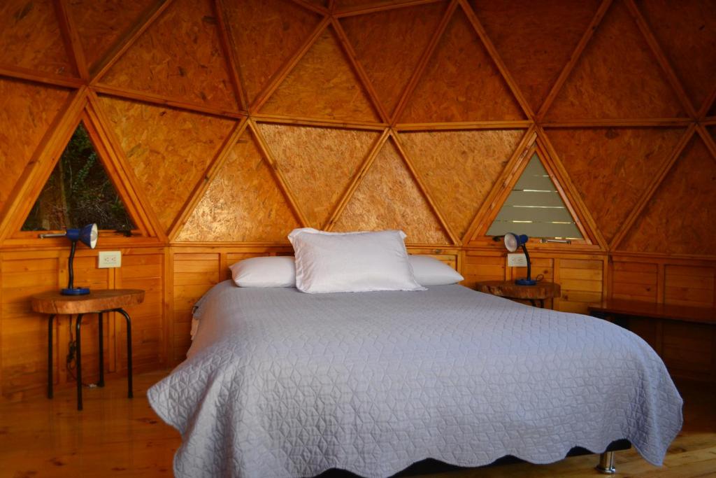 una camera da letto con un letto in una stanza di legno di Arrecife Glamping a Guatavita