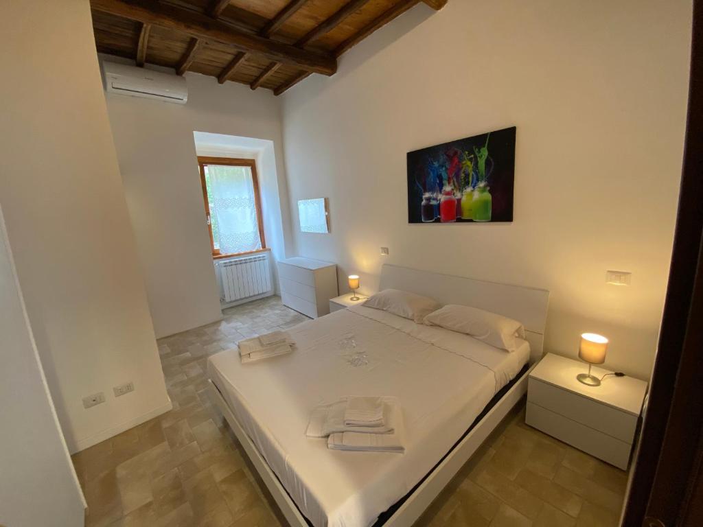 a bedroom with a large white bed with two lamps at Sasso Grosso House in Ronciglione