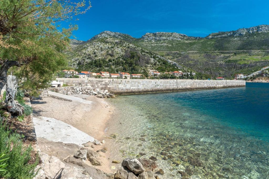 a beach with a retaining wall and the water at Double Room Trstenik 4566c in Trstenik