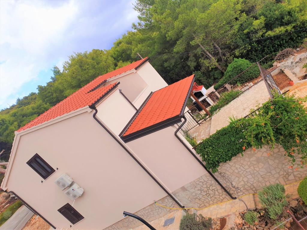 a white house with an orange roof and trees at Apartments with a parking space Rukavac, Vis - 8496 in Rukavac