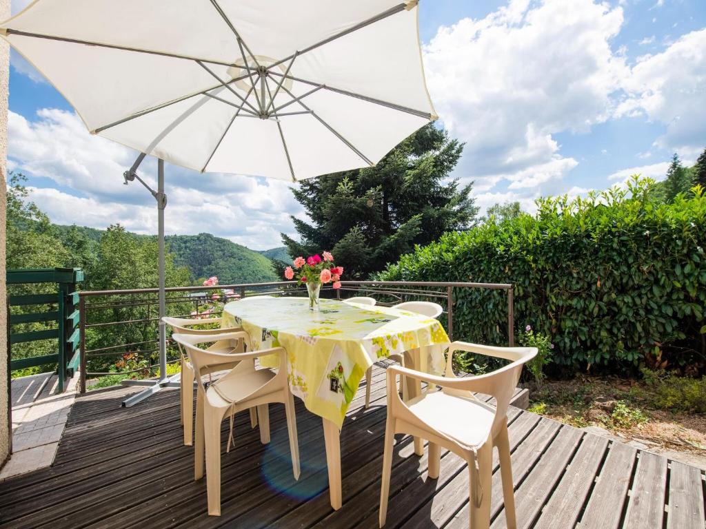 a table and chairs on a deck with an umbrella at Inviting holiday home in Miremont with garden in Miremont