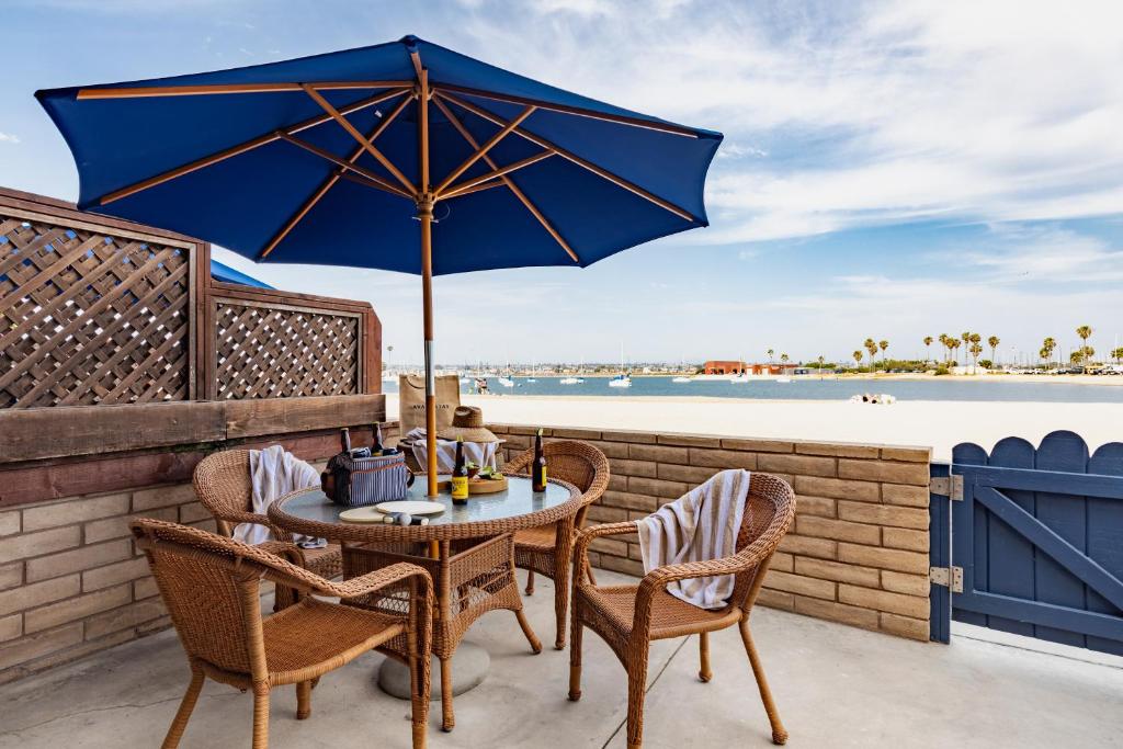 a table with a blue umbrella on a patio with the beach at Bay View II by AvantStay Ocean View Mission Beach Home on the Sand in San Diego
