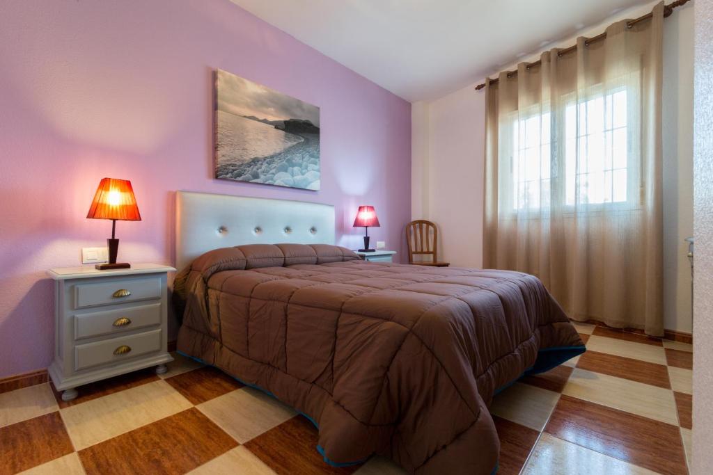 Los AlbaricoquesにあるHostal Rural Albaの紫の壁のベッドルーム1室、ベッド1台(ランプ2つ付)