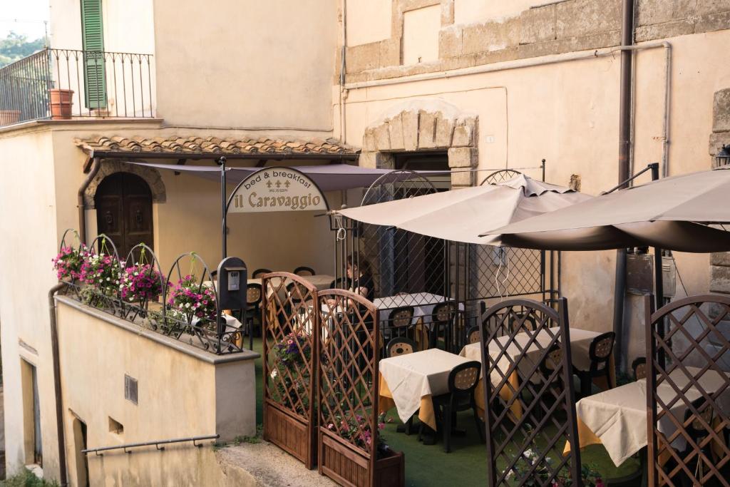 un ristorante con tavoli e ombrelloni su un balcone di il Caravaggio b&b a Caprarola