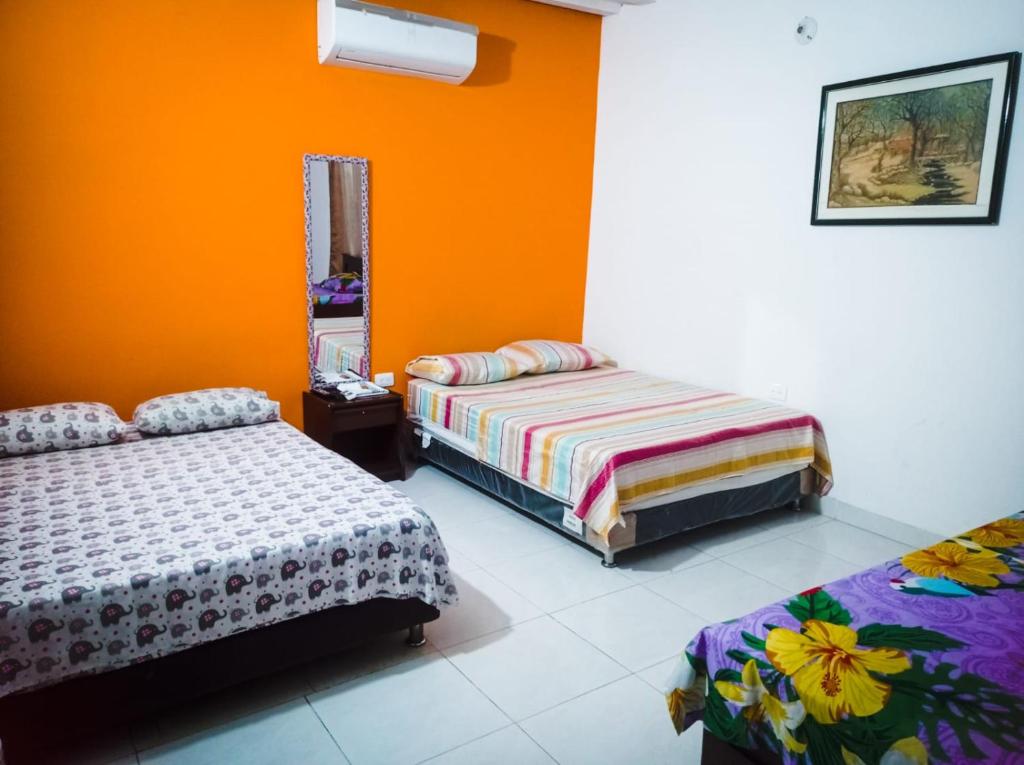 1 dormitorio con 2 camas y pared de color naranja en Hotel Acuarius en Cúcuta