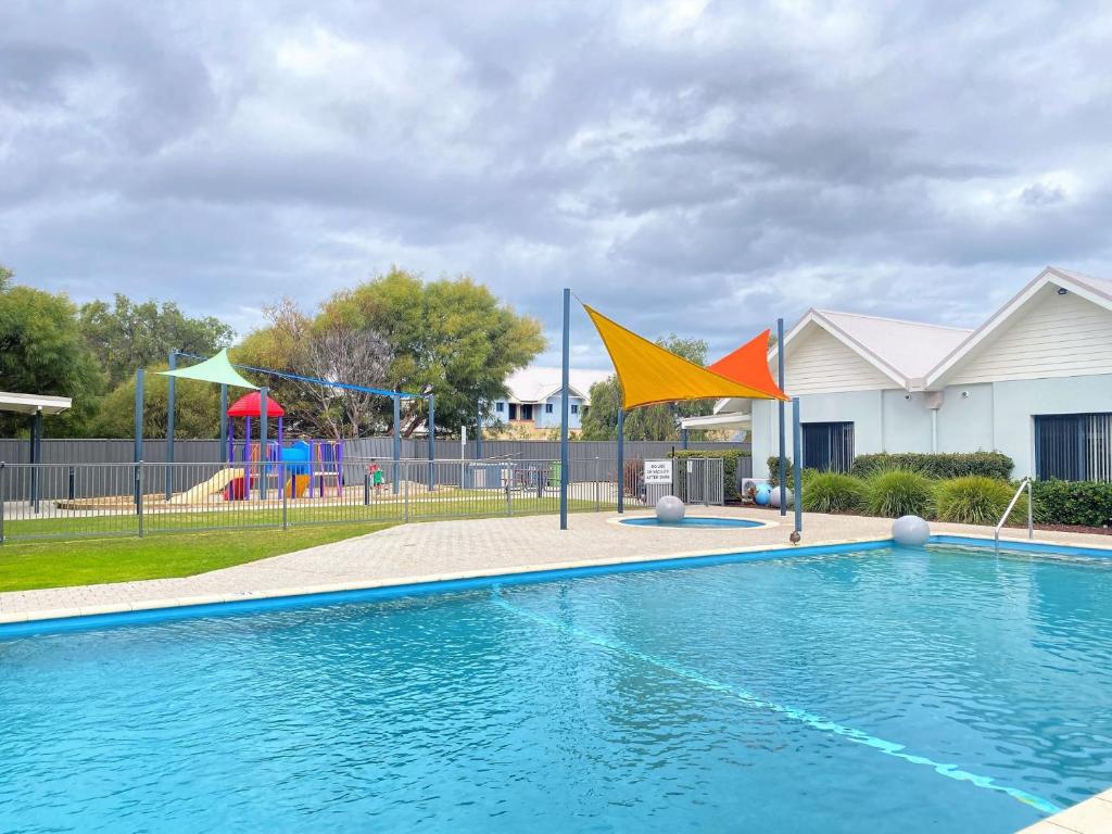 a swimming pool with flags next to a playground at By the Beach in Broadwater