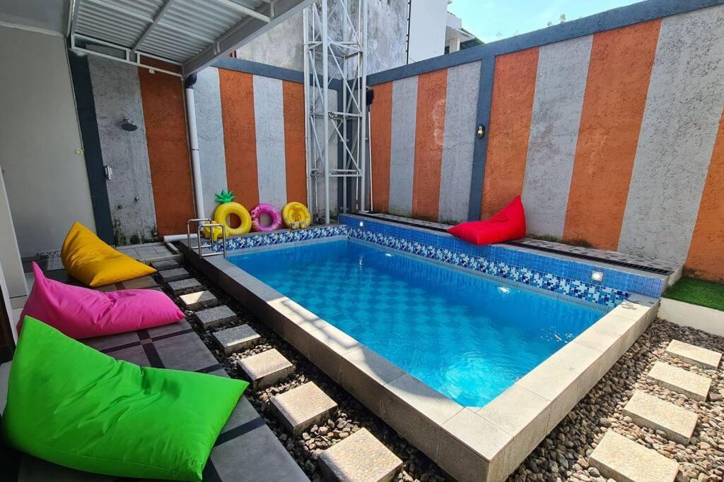 a swimming pool with colorful pillows next to a building at Oemah Wisata RinginSari -Full House, 5 Bed Rooms- in Kalasan