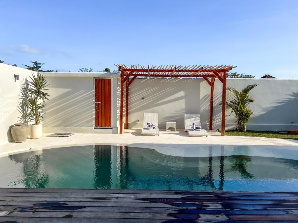 a swimming pool in front of a house with a pavilion at Moana Villa & Suites Bingin in Uluwatu