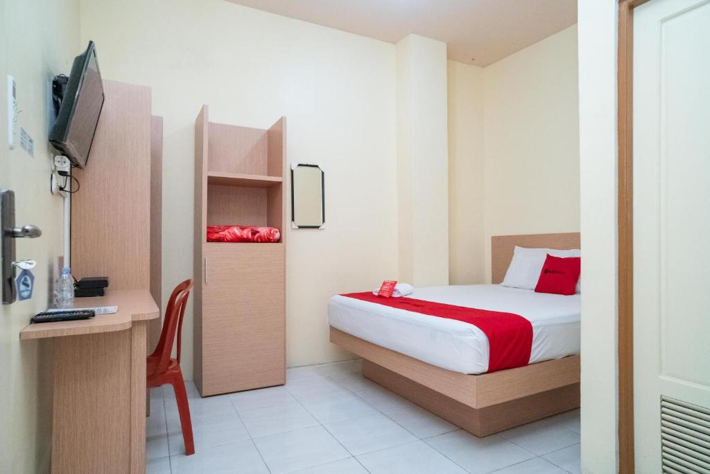 een slaapkamer met een bed, een bureau en een televisie bij RedDoorz Syariah near Taman Siring 2 in Banua Anyar
