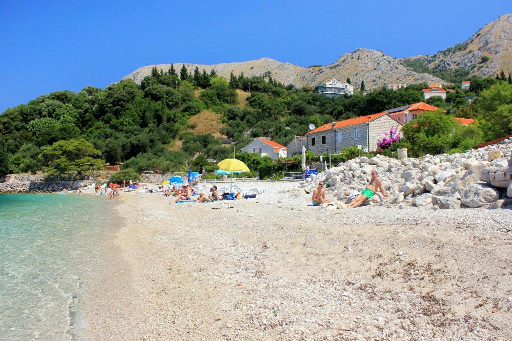 un groupe de personnes assises sur une plage dans l&#39;établissement Apartments by the sea Plat, Dubrovnik - 2136, à Mlini