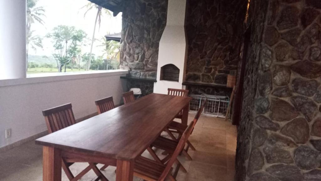 ein Esszimmer mit einem Holztisch und einem Steinkamin in der Unterkunft Villa met zeezicht / nieuwstaat / gratis parkeren in Porto Seguro