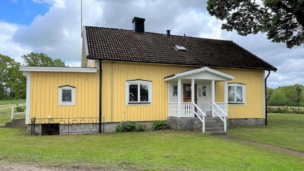 a yellow house with a white door at Vegby Bolsgård "Annexet" in Moheda
