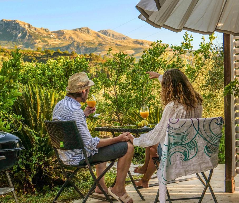 Ein Mann und eine Frau sitzen an einem Tisch mit Weingläsern in der Unterkunft Cuore Della Valle in Cefalú