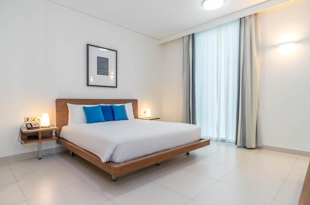 sypialnia z dużym łóżkiem z niebieskimi poduszkami w obiekcie Adagio Abu Dhabi Al Bustan w Abu Zabi