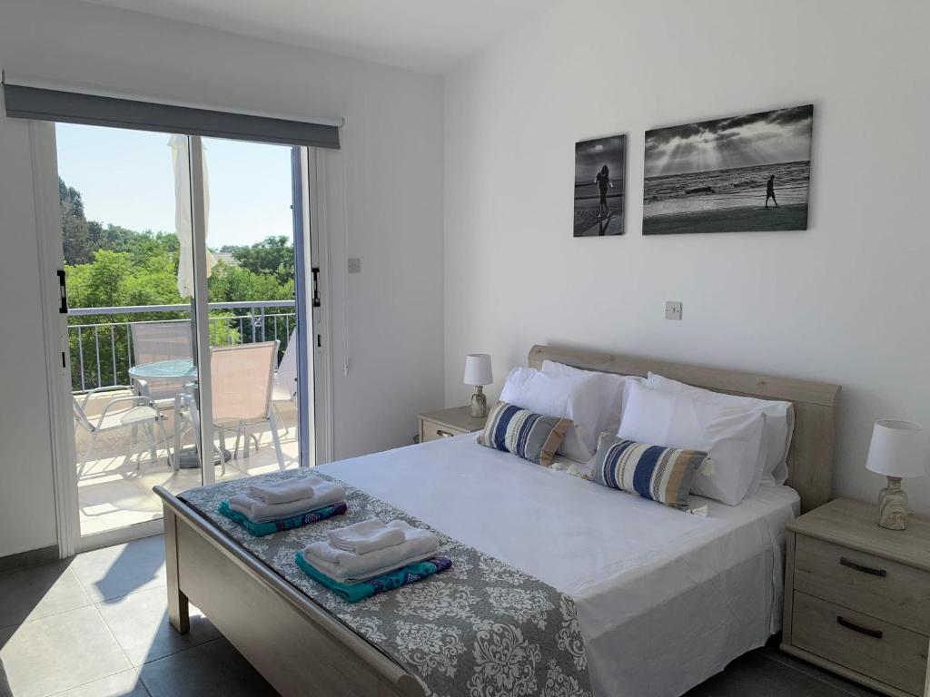 a bedroom with a large bed and a balcony at Paradise Gardens 3 - superb 1 bed apartment in Paphos