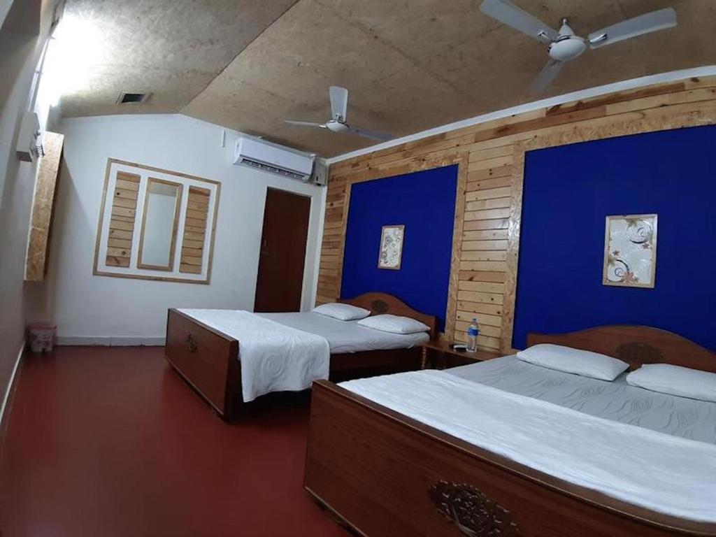 1 dormitorio con 2 camas y pared azul en Royal Cottage, Anaimalai room 4, en Pollachi