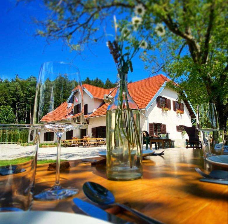 une table avec des verres et un vase avec des fleurs. dans l'établissement OPA Resort, à Šmartno ob Paki