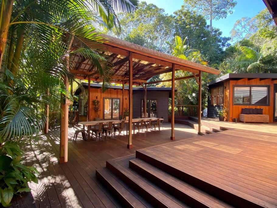 a house with a wooden deck with tables and chairs at Ananda Eco House - Eco Rainforest Retreat in Montville