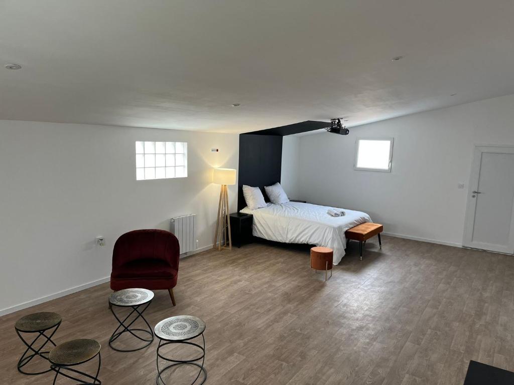 a room with a bed and a chair and tables at NG SuiteHome - Queven - Balnéo - Netflix - Wifi in Quéven