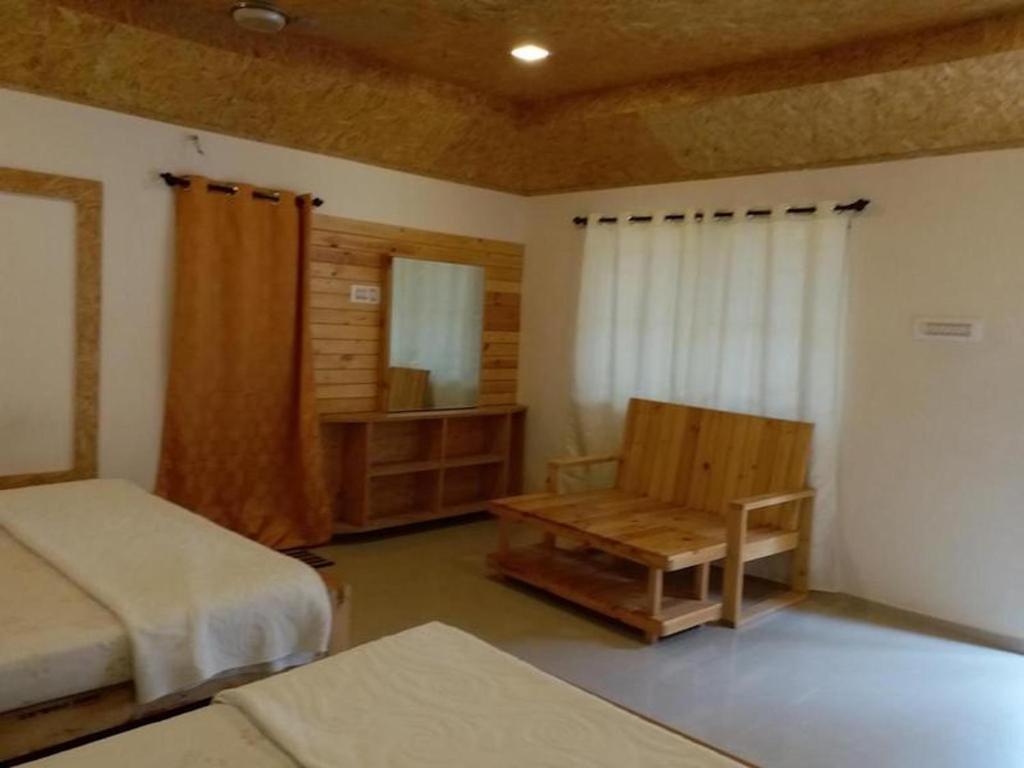 1 dormitorio con 2 camas, silla y espejo en Royal Cottage, Anaimalai room 5, en Pollachi