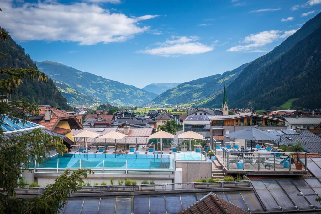 a resort with a pool and mountains in the background at MANNI das Hotel in Mayrhofen