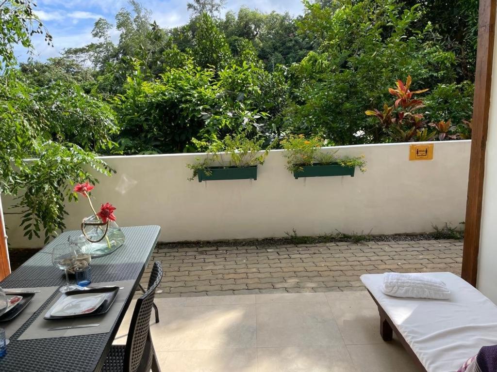 a patio with a table and chairs and a fence with plants at Le Comfort (self catering) in Anse Royale