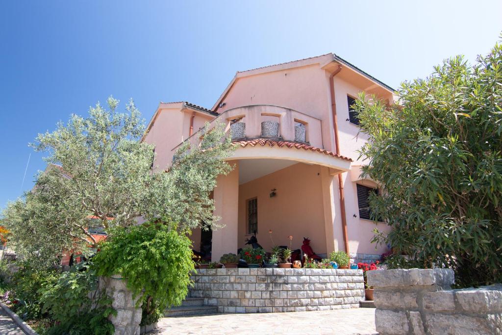 a pink house with trees in front of it at Apartment Slavica with private Balcony and Parking lot in Punat