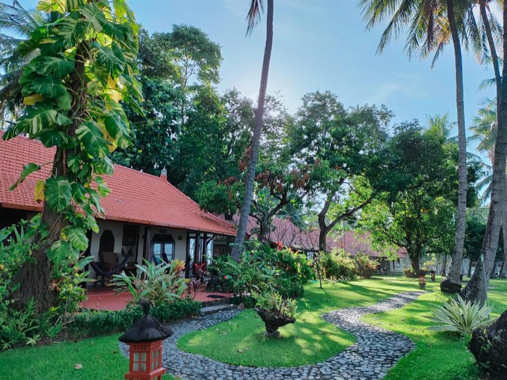 a garden in front of a house with palm trees at Gaia-Oasis Beach Resort in Tejakula