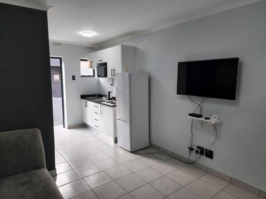 a kitchen with a refrigerator and a tv on the wall at Grace Villas 7 in East London