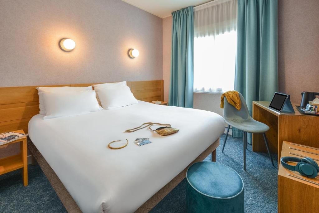 ein Hotelzimmer mit einem großen weißen Bett und einem Stuhl in der Unterkunft Sure Hotel by Best Western Centre Beaune in Beaune