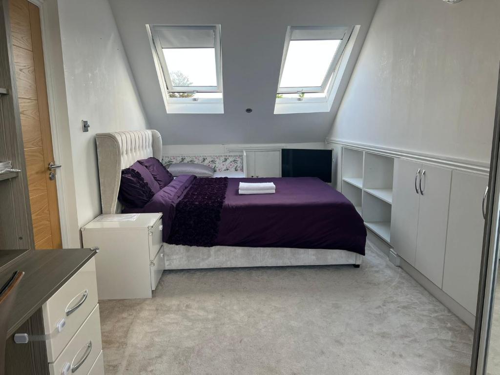 um quarto com uma cama roxa e 2 janelas em Deluxe Homestay near Tottenham Hotspur Stadium em Londres