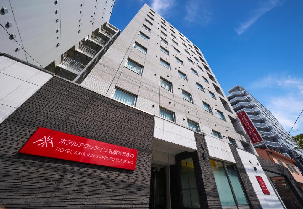 a building with a red sign on the side of it at Hotel Axia Inn Sapporo Susukino in Sapporo