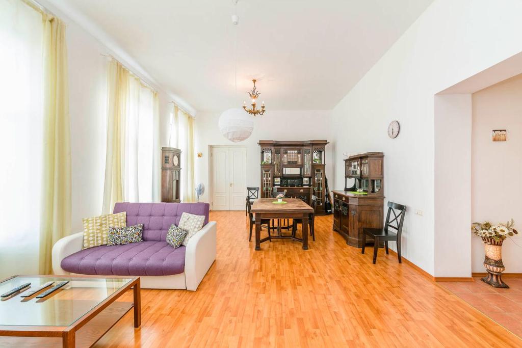 sala de estar con sofá púrpura y mesa en Feelathome Apartments on Millionnaya, en San Petersburgo