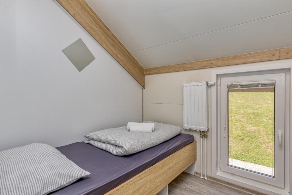 Cette petite chambre comprend un lit et une fenêtre. dans l'établissement Three Stars Luxury House ART-PE with pool and SPA pool, à Trebnje