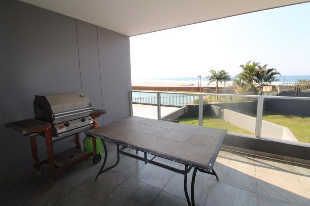 a balcony with a table and a grill with a view of the beach at Boulevard 113 in Margate