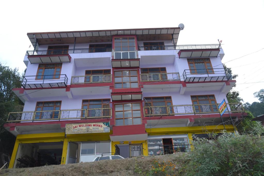a tall white building with red windows and balconies at Indu BNB Shimla in Shimla