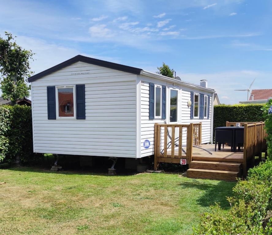 a white tiny house with a wooden deck at Bienvenue chez Anaïs ! in Biville-sur-Mer