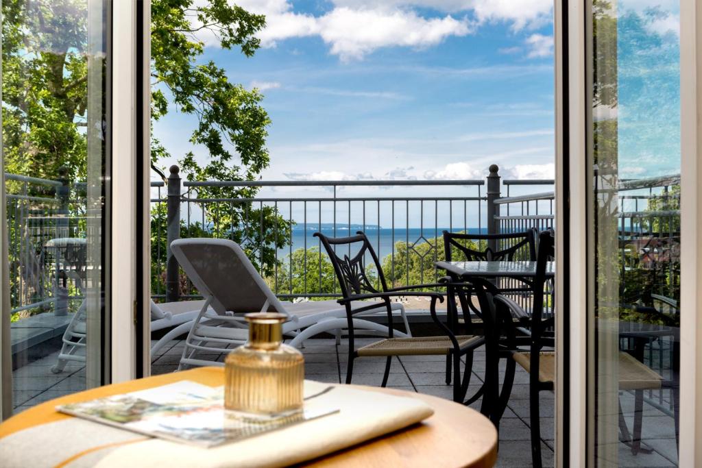 a room with a balcony with a table and chairs at Vju Hotel Rügen in Göhren