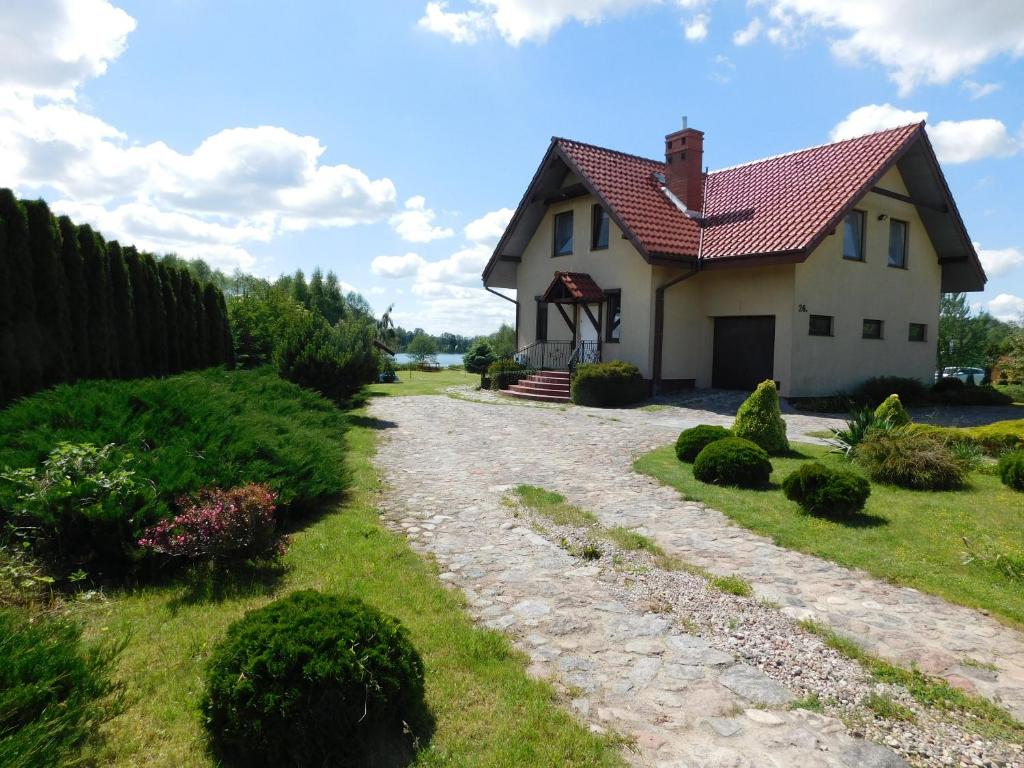 ein Haus mit rotem Dach und Schotterstraße in der Unterkunft Wypoczynek na Mazurach u Kamili in Konopki Wielkie