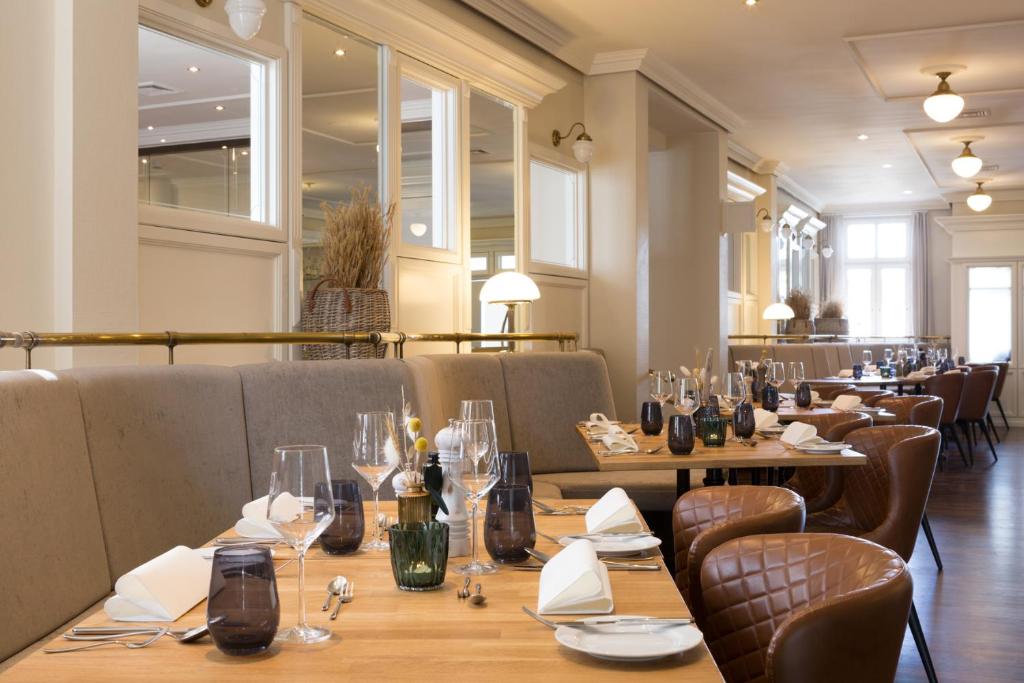a restaurant with wooden tables and chairs and glasses at Vju Hotel Rügen in Göhren