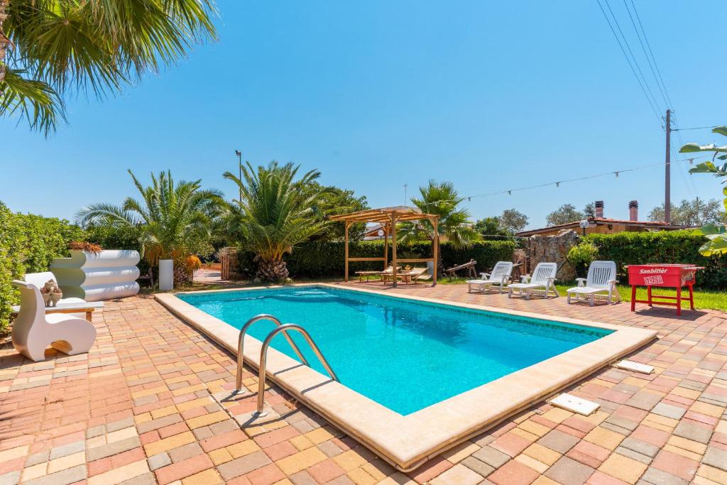 una piscina in un cortile con sedie e alberi di Villa Relax a Galatone